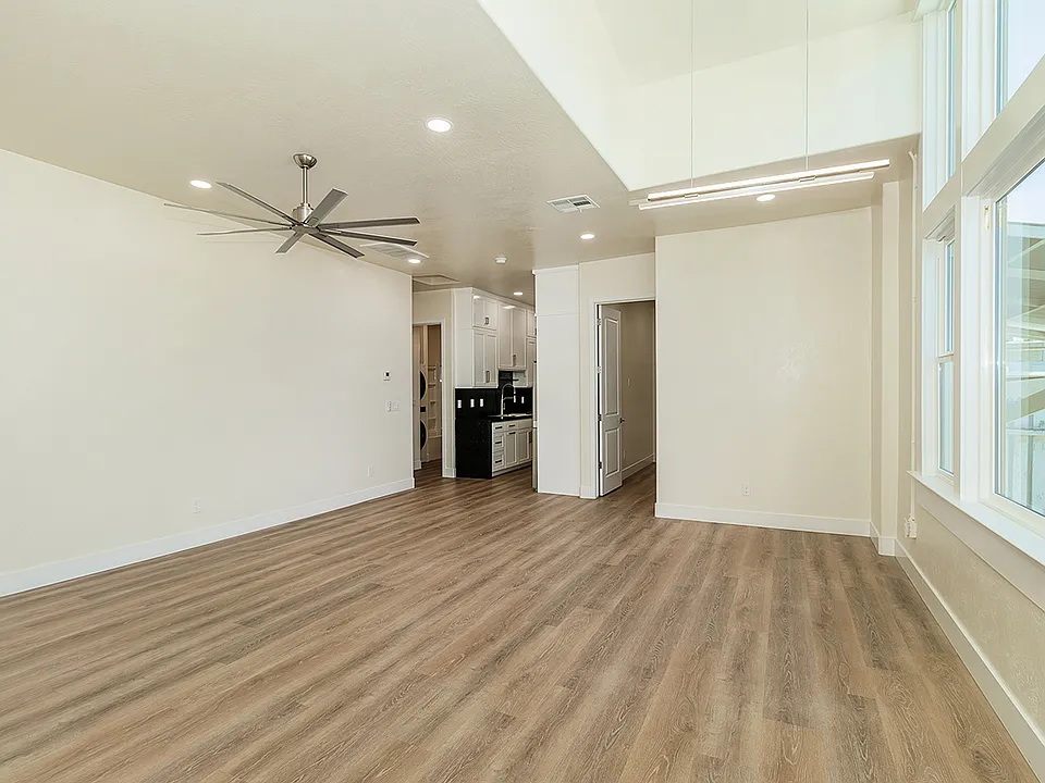 Large High Vaulted Ceiling with Custom Fan, Amazing Large Windows, Luxury Vinyl Plank Flooring, And Automatic Roll Down Shades.