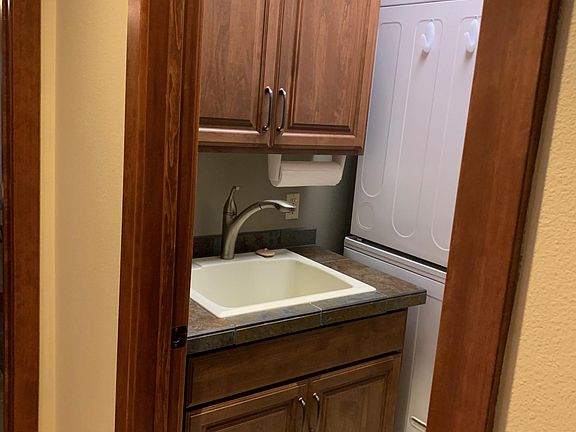 Laundry room with stacking washer and dryer, wet sink and storage cabinets