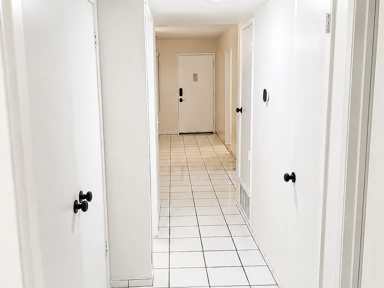 Bright interior hallway with tile flooring and access to bedrooms, bathrooms, and main living areas.