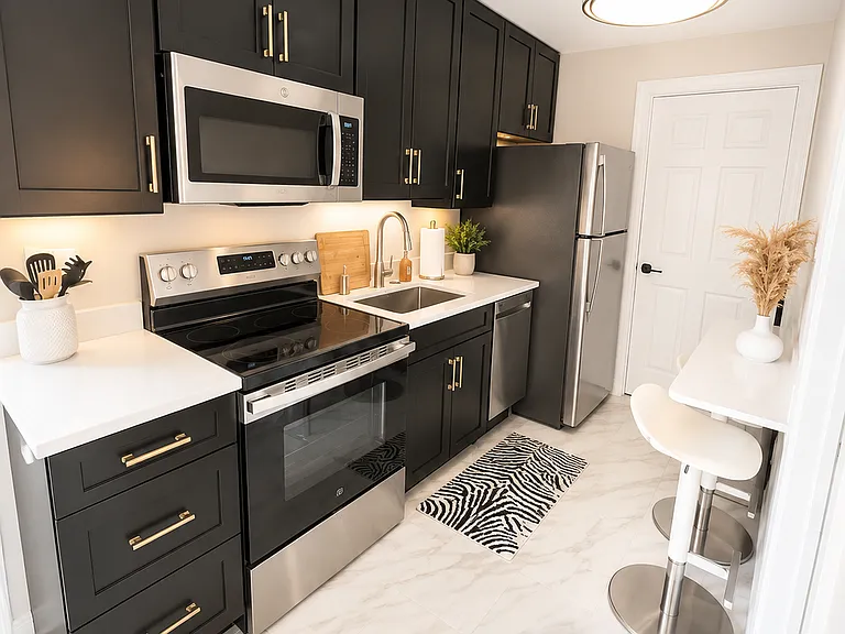 Modern guest suite kitchenette designed for comfort and independence, featuring black cabinetry, updated countertops, stainless steel appliances, cooking essentials, and a clean, functional setup perfect for families, couples, and business travelers.