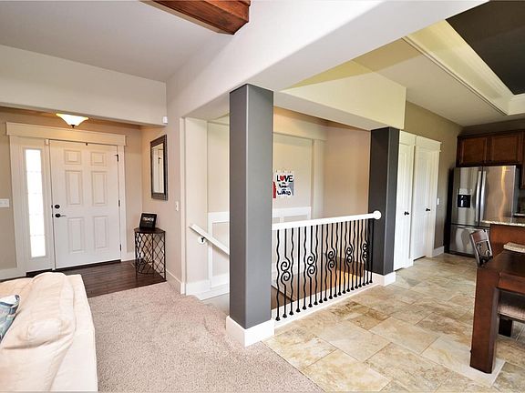 Here is a broader view of the entry showing part of the Breakfast Room and Kitchen.  There are custom spindles on the banister leading to the walk out basement. The doors to the far right are the pantry and laundry room.