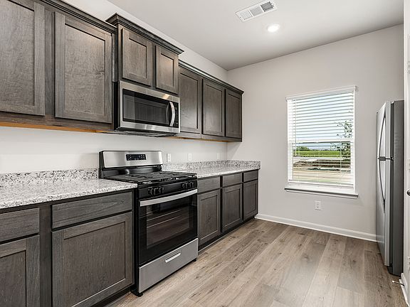 The kitchen has beautiful wood cabinetry and sprawling granite countertops.