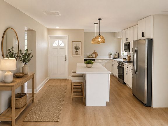 Interior entryway and kitchen. Granite countertops, stainless steel appliances, island that's perfect for entertaining.
