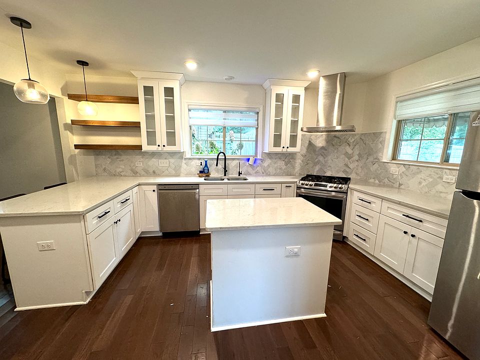 open kitchen with stainless steel appliances and gas stove, and quartz countertops.