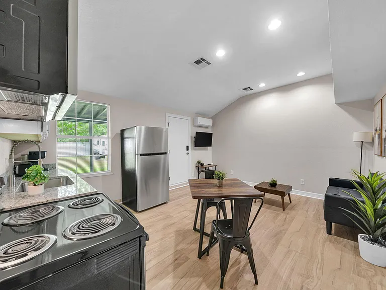 Open kitchen with stainless refrigerator, granite-style counters, and a dining nook that flows into the living area.
