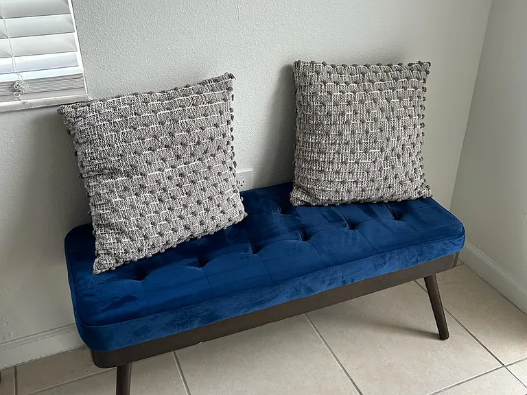 Stylish velvet bench with decorative pillows, perfect for relaxing and comfort.