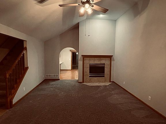 Living room with gas fireplace arched doorway leads dining room and open concept kitchen
