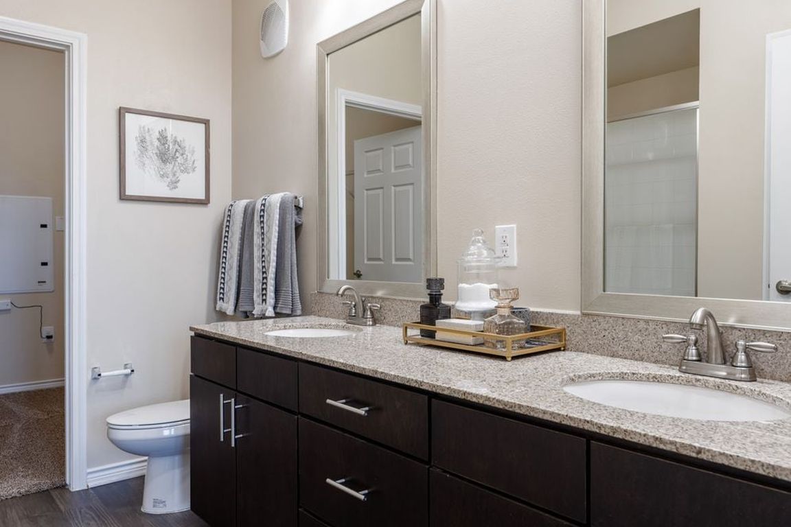 Baths with dark cabinetry, beige speckled granite countertops, and hard surface flooring