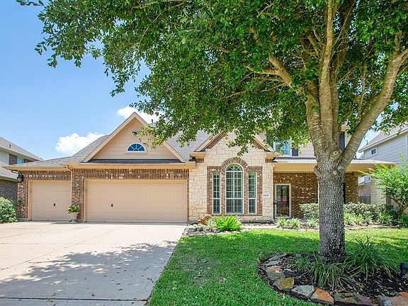 3-car garage with true 3-car driveway, brick and stone elevation, front porch and lush landscaping.