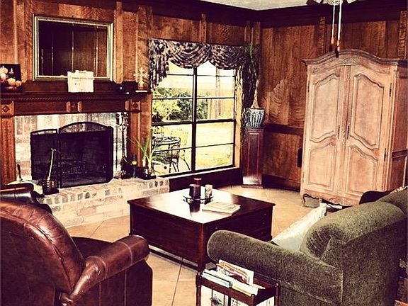 Spacious Living Room with Custom Wood Paneling and Wood Burning Brick Fireplace