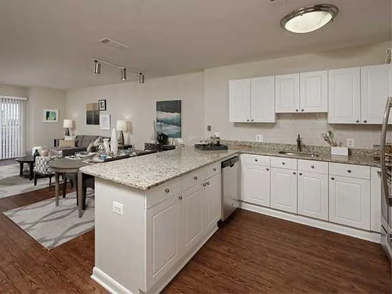 Open concept kitchen with white cabinetry, cream tile backsplash, stainless-steel appliances, granite countertops and hard surface flooring