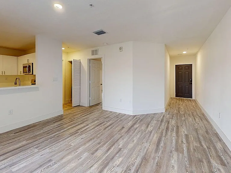 Modern open-concept apartment featuring sleek hardwood floors, elegant white cabinetry, and a stylish kitchen space.