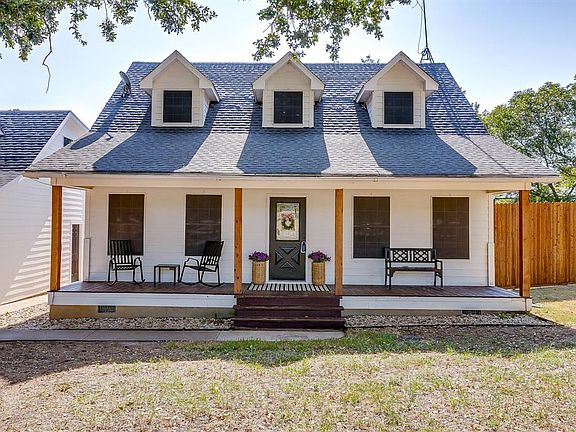 View of front of property featuring covered porch, a shingled roof, and a front yard