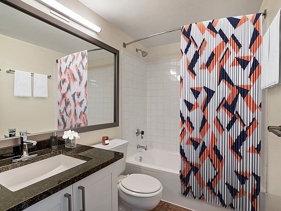 Renovated Package II bath with new white cabinetry, granite countertops, and hard surface flooring