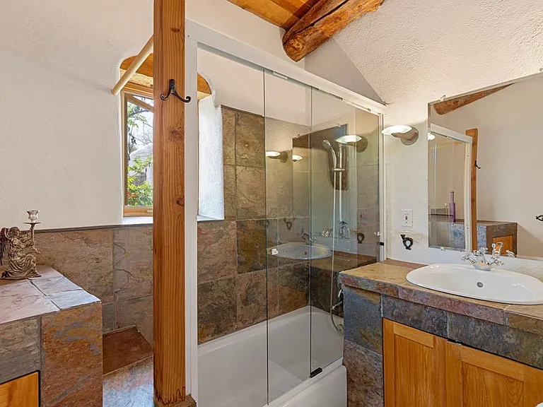 Bathroom with shower stall, sunk in bath tub and private toilet stall