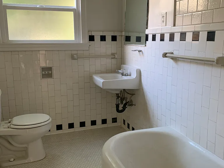 Bathroom with vintage tiles, and a tub/shower. Floor tile is being replaced