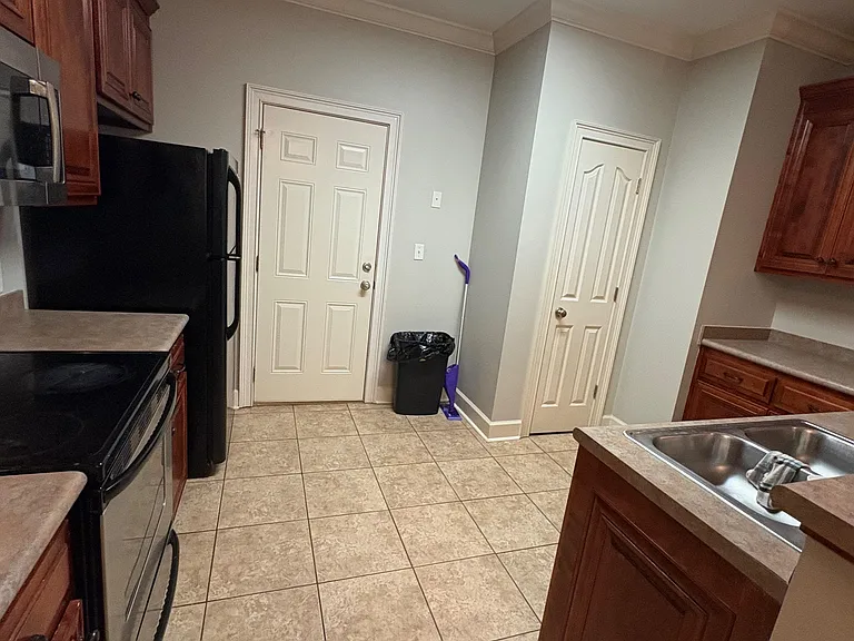 Galley-style kitchen with ample wood cabinetry, tile flooring, and a full appliance set for everyday cooking.
