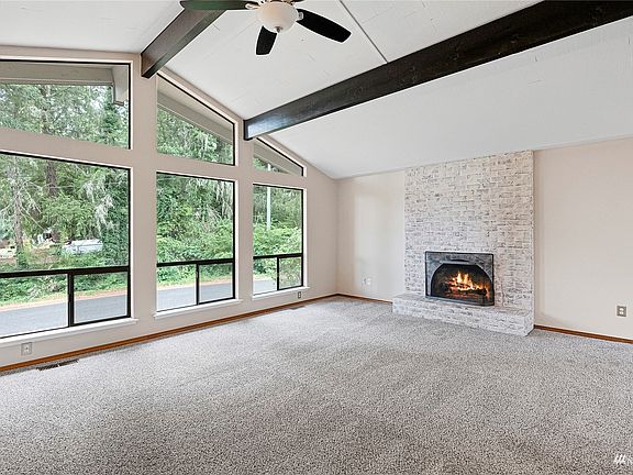 Dark wood beams compliment the high ceilings and wall of windows! The wood burning, brick fireplace makes this room a show stopper!>