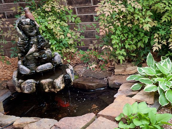 Fountain nestled in garden near front door