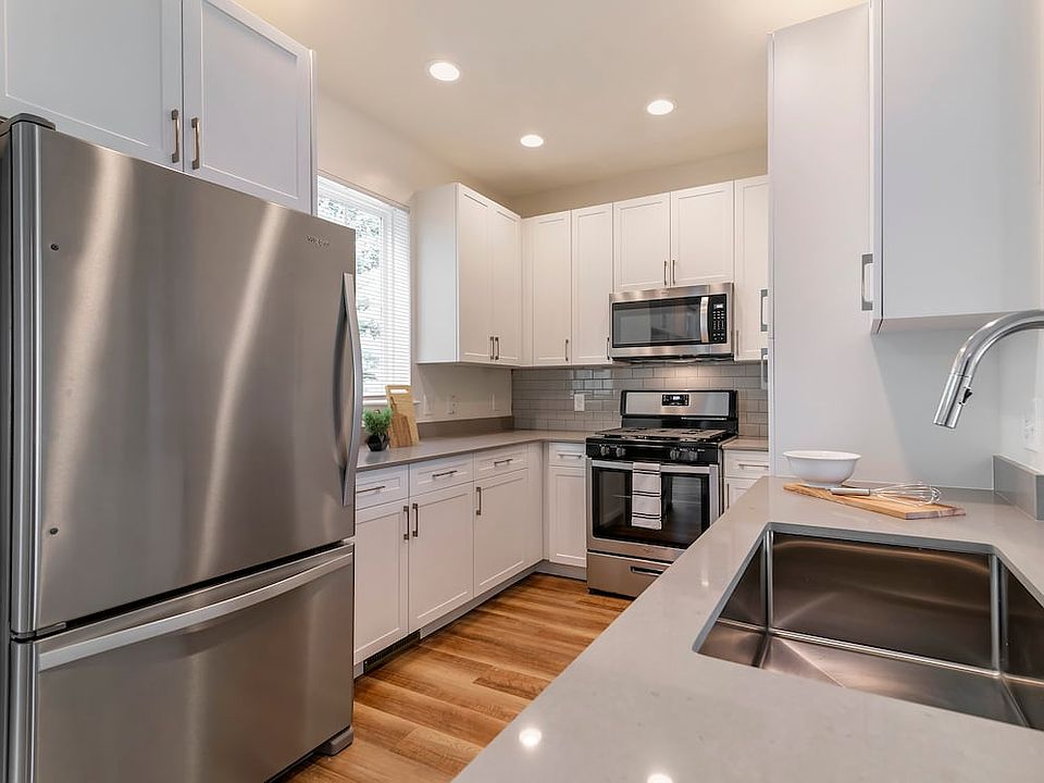 Renovated Package II kitchen with white cabinetry, grey quartz countertops, grey subway tile backsplash, stainless steel appliances, and hard surface flooring