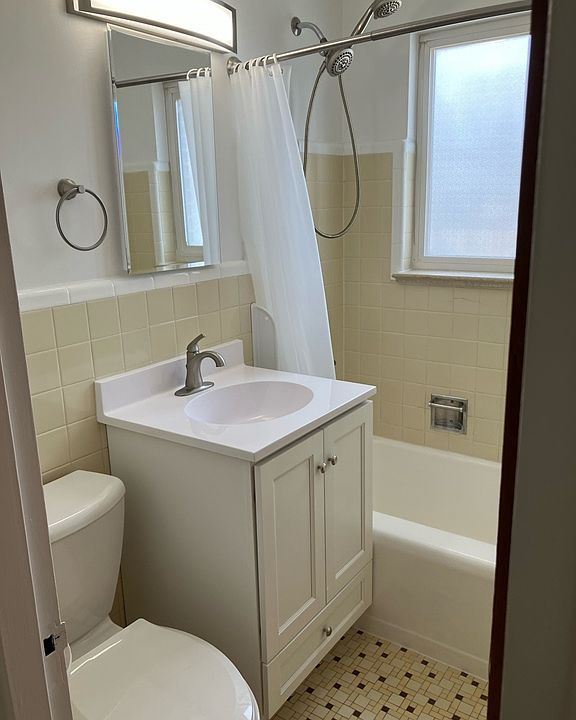 Clean refreshed bath with new vanity, faucet, medicine cabinet, light, curved shower rod, and new shower valve.