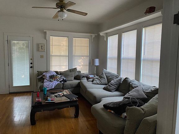 Living Room - (facing front door) original hardwood floors, 9 ft. ceiling, 5 large windows with blinds, shleving above windows, ceiling fan, opens onto Dining Room through French doors.