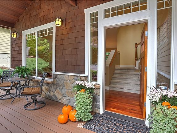 Inviting covered front porch opens to soaring two-story foyer with gleaming hardwood floors and wrought iron staircase.