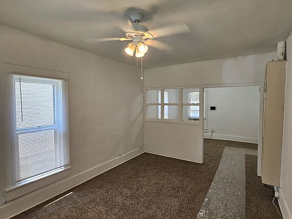 Living room standing at front doorway; bedroom is on right. Dining room is beyond the partition. Kitchen is on right, off the dining room