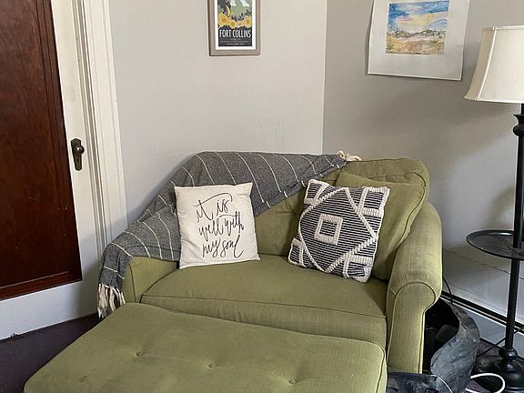 Corner area of living room accomodates a large overstuffed chair and ottoman