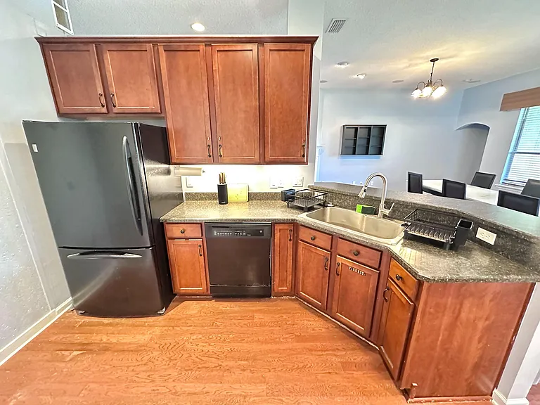 Galley kitchen with ample wood cabinetry, full-size appliances, and a breakfast bar with sink overlooking the dining area.