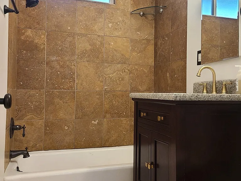 Bathroom has travertine tile walls and floors.