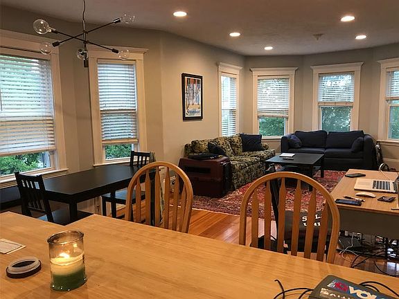 View of living room and dining area. Picture windows look out to a residential street.
