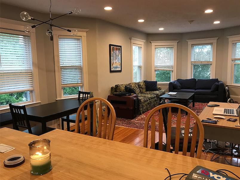 View of living room and dining area. Picture windows look out to a residential street.