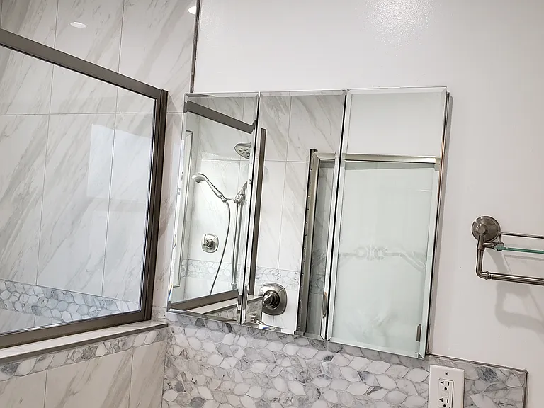 Bathroom mirror above vanity. Shower is on the left.
