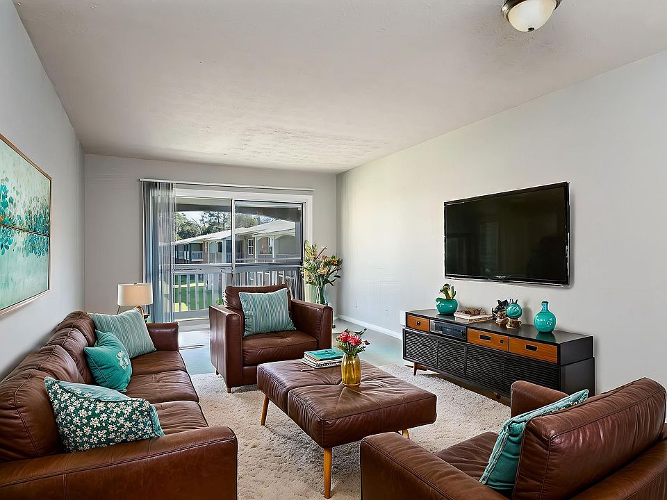 Inviting living room with elegant leather sofas, vibrant turquoise accents, and a sleek wall-mounted TV, perfect for relaxation and entertainment.