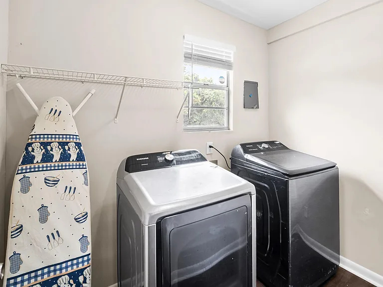 Dedicated laundry room with side-by-side washer and dryer, plus a wall-mounted shelf for storage and supplies.
