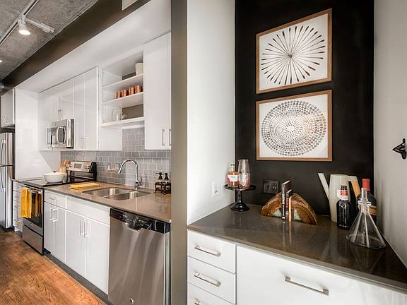 Kitchen with white cabinetry, quartz countertops, stainless steel appliances, tile backsplash and hard surface flooring