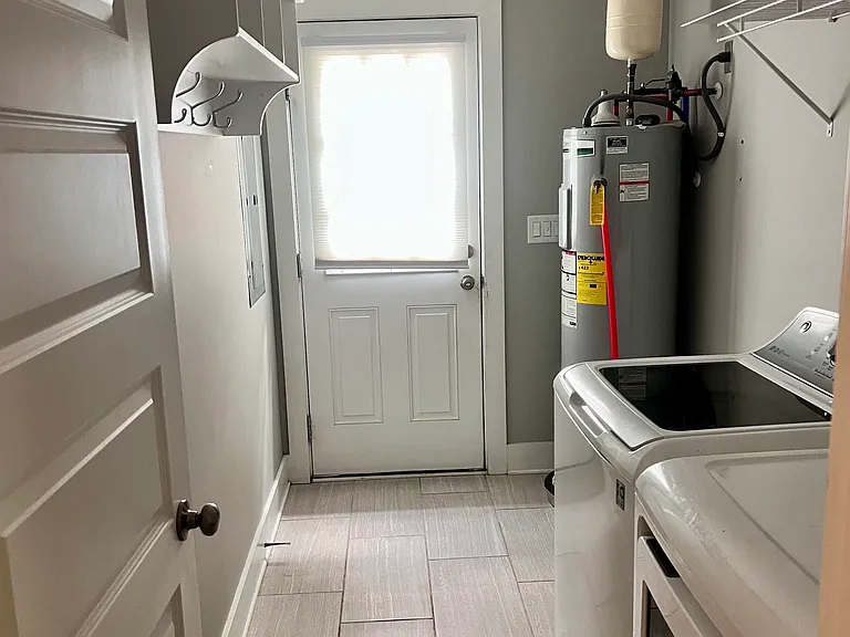 Laundry room with included washer and dryer. Door to side porch with backyard and driveway access