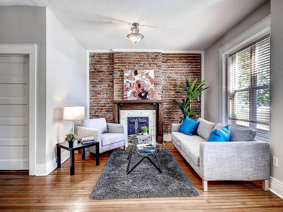Living Room _ Spacious living room with exposed brick and original fir floors that add character and charm. The door on the left is the downstairs full bathroom.