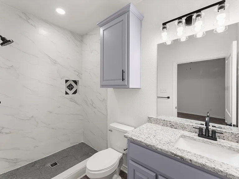 Bathroom featuring a walk-in shower with white marble-look tile walls, a black penny tile floor, and a recessed niche with decorative tile