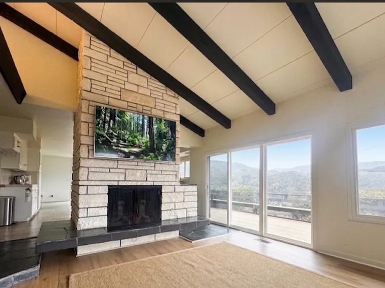 Living room with vaulted ceilings, wood beams and wood buring fire place, upper level.