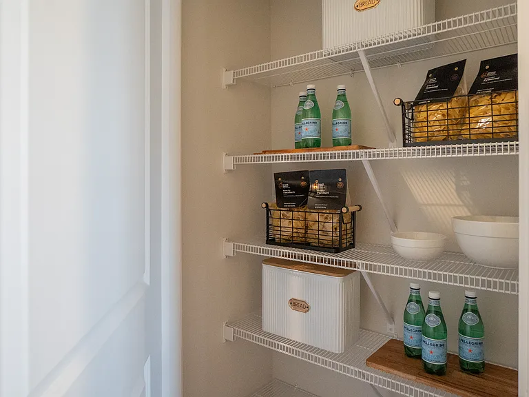 Closed off kitchen pantry with wide shelving and ample storage.