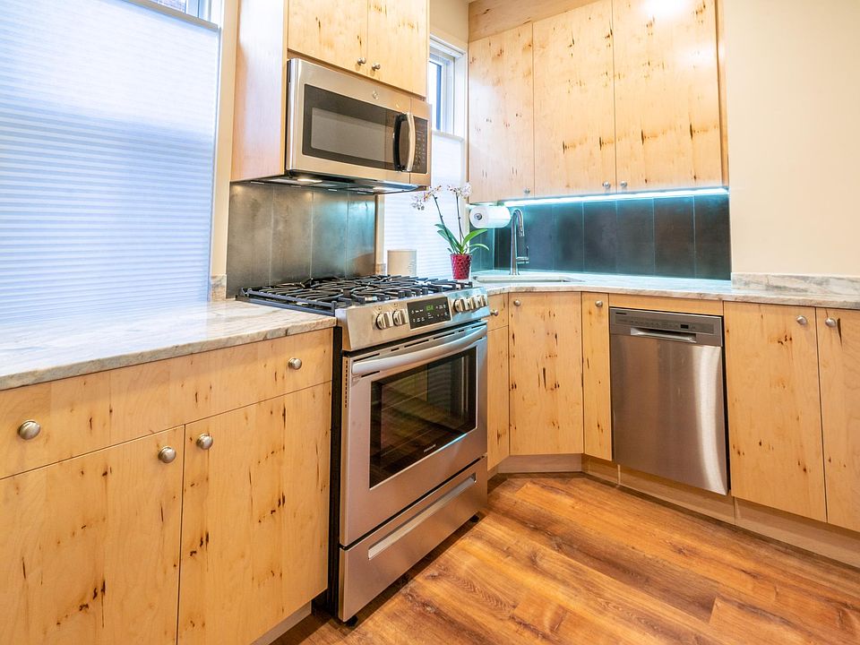 Kitchen with stainless steel appliances, stainless steel backsplash, quartz countertop, underneath the cabinet lighting, recessed lighting and ceiling fan above eat in kitchen.