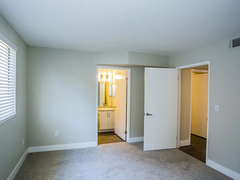 Bedroom with large baseboards, two-tone paint, tons of natural light, and door to bathroom.