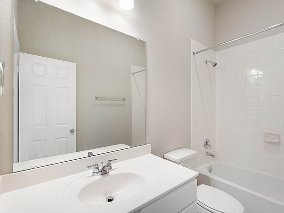 The secondary bath features tile flooring, white cabinetry and light countertops and a shower tub co