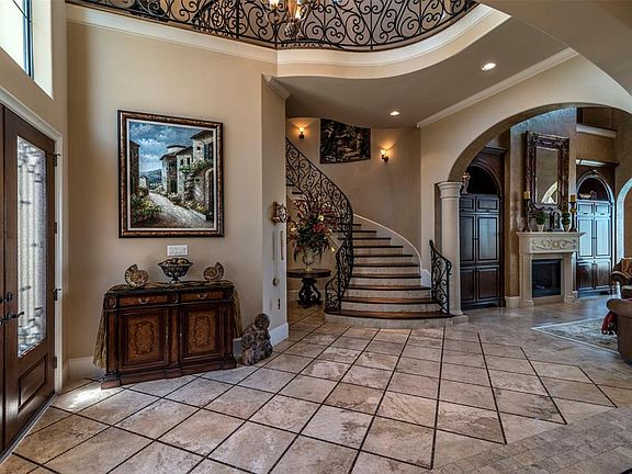 The foyer has a soaring ceiling and beautiful wrought iron railing that overlooks the entry! Note the beautiful wall sconce lights along the curved wall in the staircase.