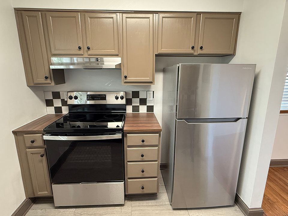 New stove and refrigerator with ceramic tile backsplash and freshly painted cabinets.