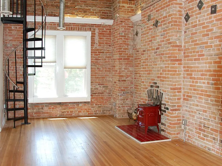 Living Room with tons of light and hardwood floors. Red fireplace.