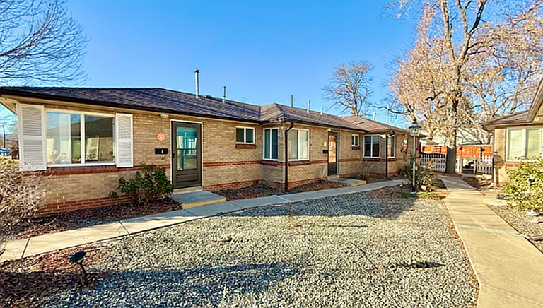 Charming single-story brick apartment with large windows, nestled in a serene, landscaped community.