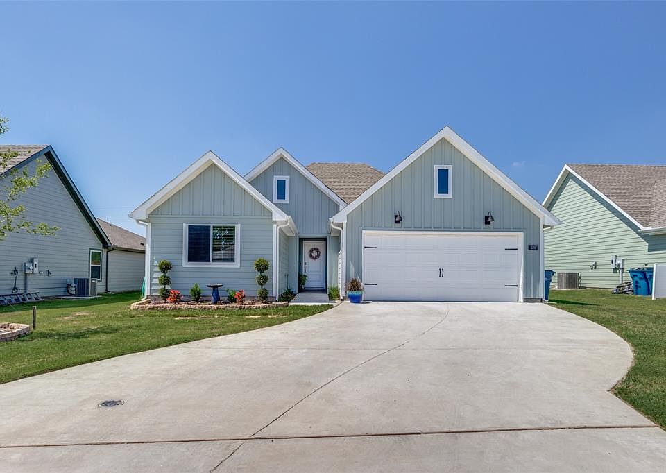 View of front of house featuring board and batten siding, concrete driveway, a front yard, and central air condition unit